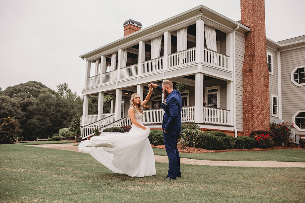 Newly married couple twirling in front of The Barn at Oak Manor