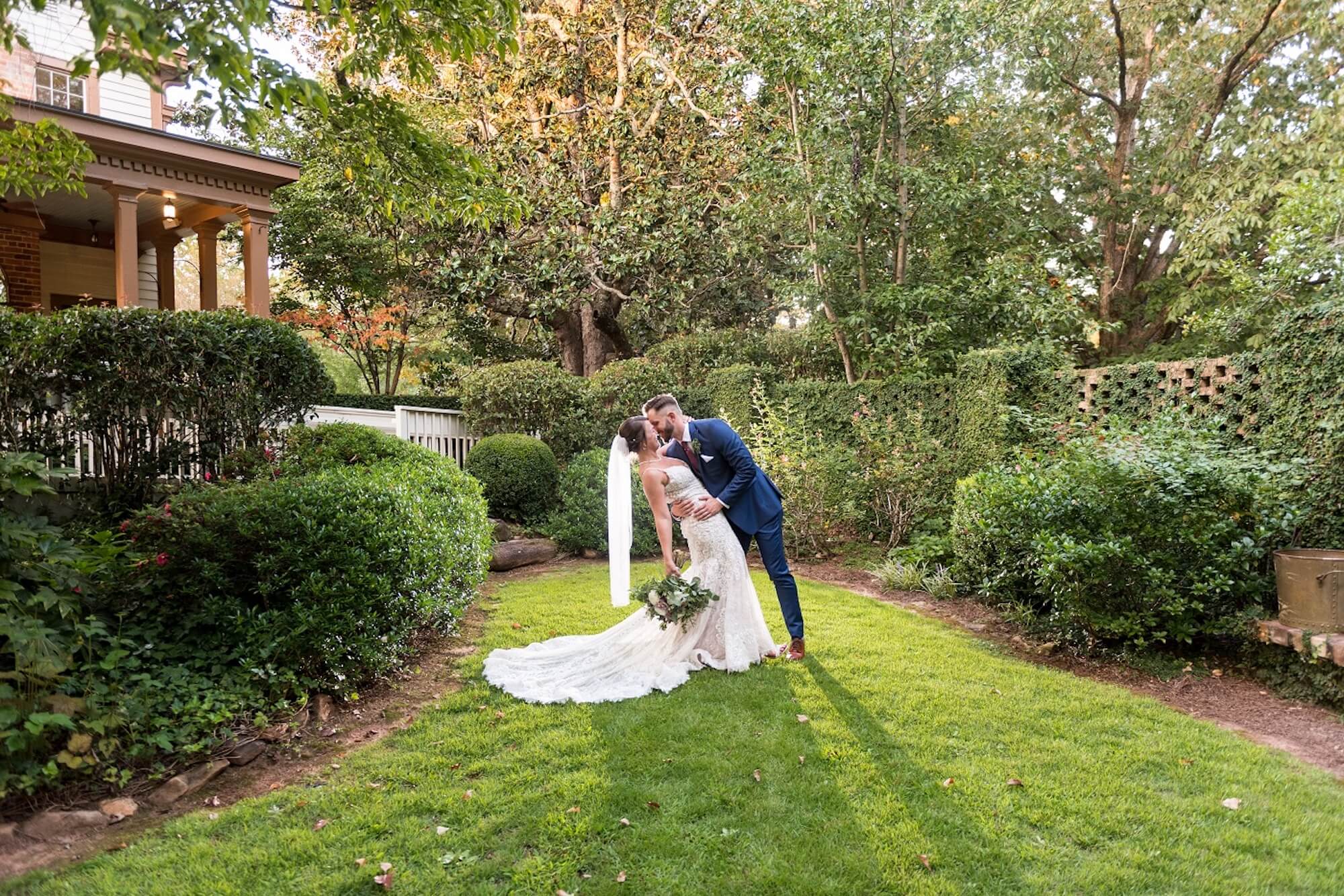 Newlyweds kissing on a green lawn